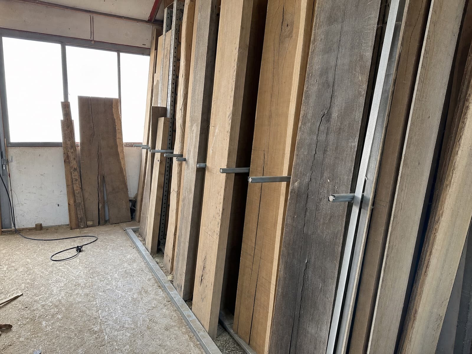 Bretter und Bohlen stehend in einem Kragarmregal an der Hallenwand