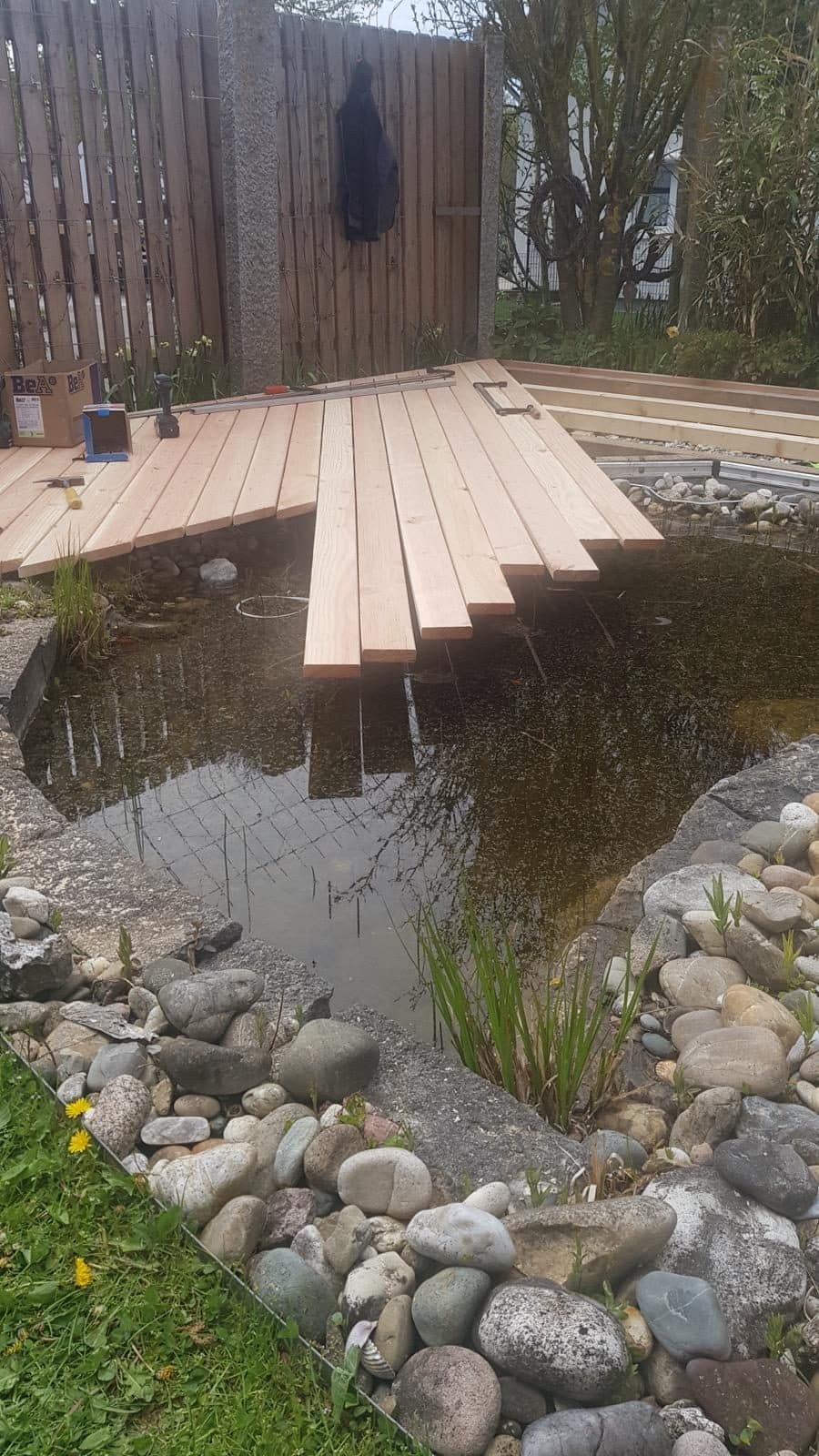 Terrassendielen werden am Gartenteich verlegt