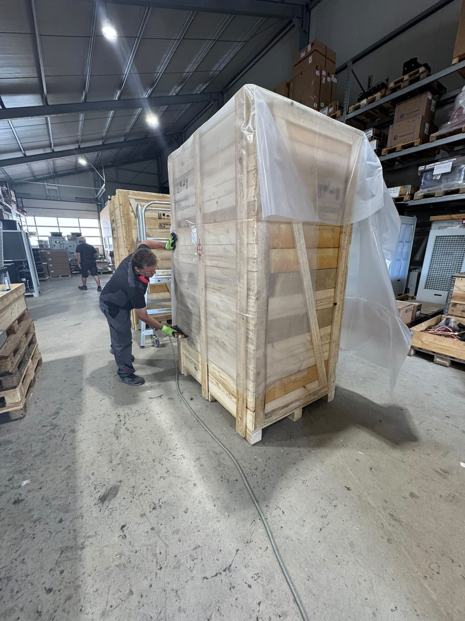 Mitarbeiter verpackt eine Anlage in der Halle des Kunden